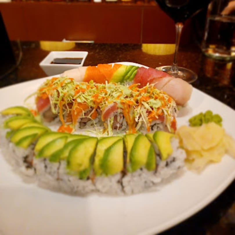 Platter of Mikado Ryotei sushi rolls, including avocado, tuna, and salmon, with soy sauce and wine.